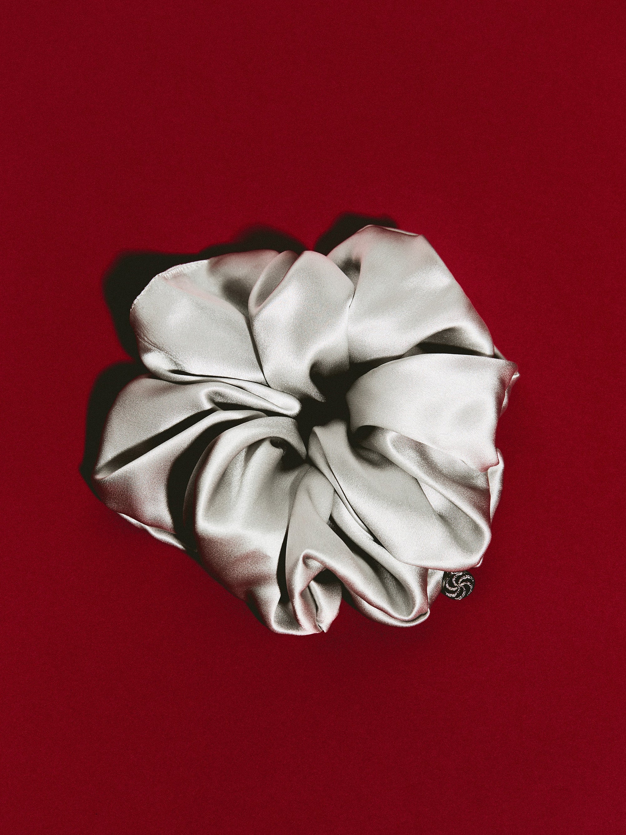 Oversized silk scrunchie in Silver Gray - packshot, burgundy background - CONTOUROSE