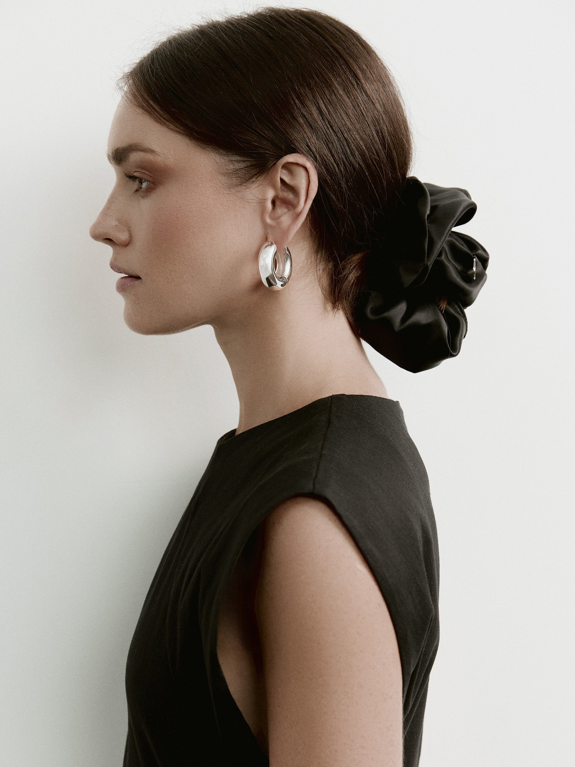 Model wearing an oversized black silk scrunchie by Contourose — a luxury hair accessory made in Europe from Italian silk.